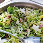 Close-up of fresh vegetable salad with cucumbers, cabbage, and radishes, served in a stainless steel tray.