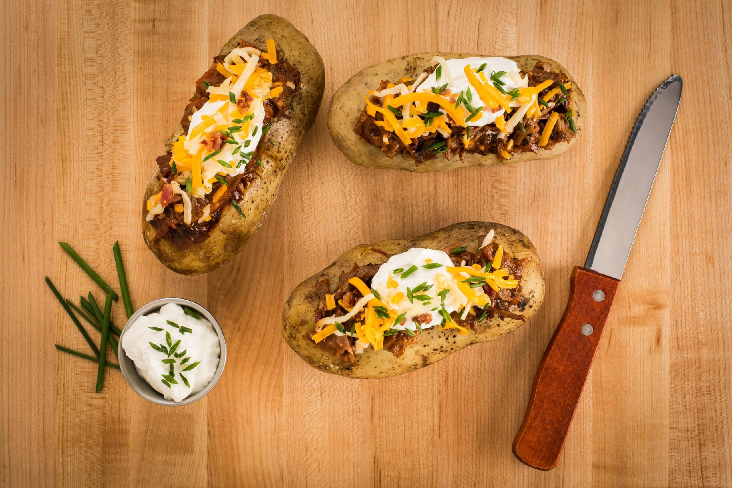 baked potatoes topped with chili, cheese and sour cream